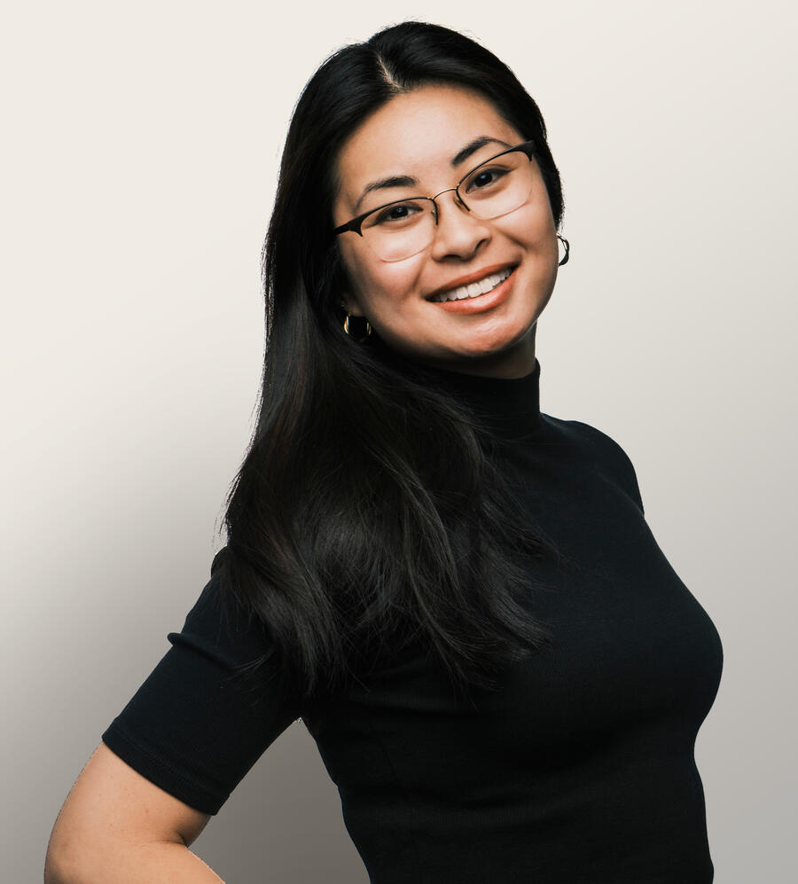 Headshot photo of Asian woman in a black mock turtleneck smiling and wearing glasses.